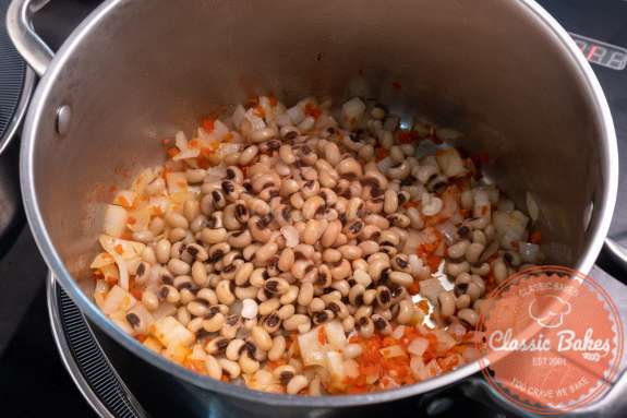 Rinsed beans being added to the pot of vegetables 