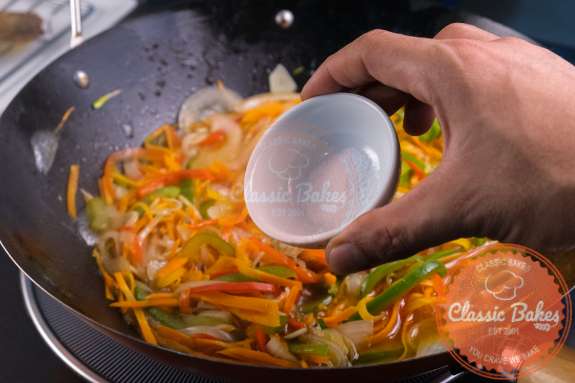 Seasoning being added to Escovitch vegetables 