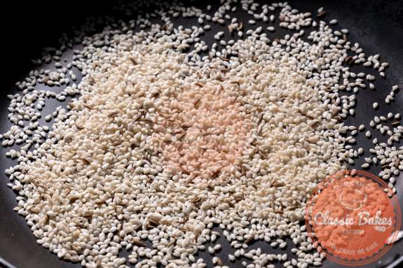 Sesame and cumin seeds being toasted in a pan 