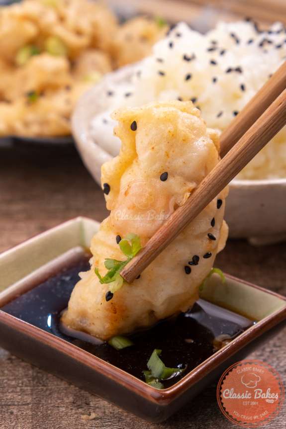 Sideview of chicken tempura being dipped in sauce 