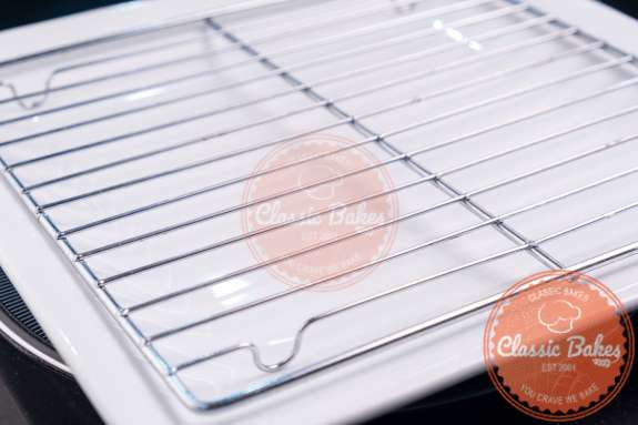 Sideview of a lined baking sheet with a cooling rack on top 