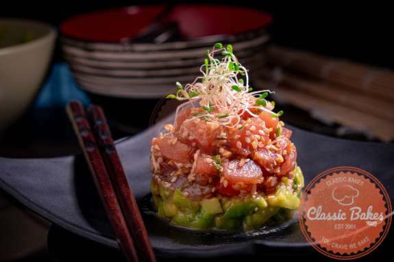 Sideview of tuna tartare assembled on a plate with chopsticks on the side 