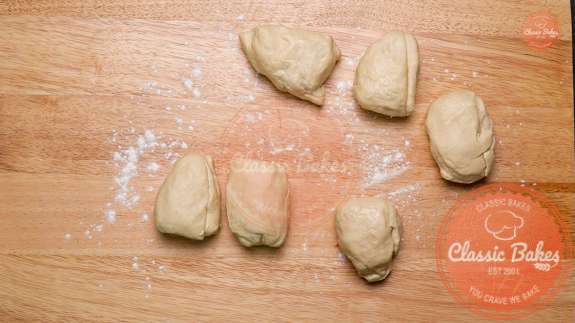 six small balls of dough being rolled on a floured countertop 