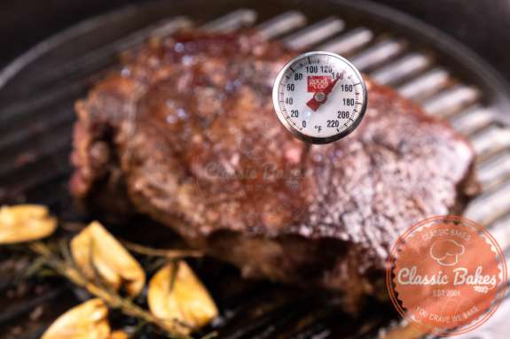 A thermometer inserted into a ribeye steak 