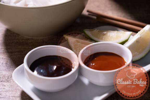 Two ramekins with hoisin sauce and sriracha sauce 