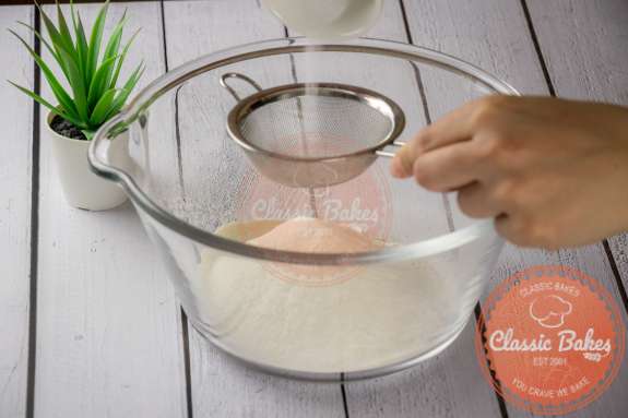 Water being poured into flour in a glass bowl 