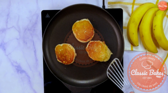 Pancakes being flipped in a skillet using a spatula