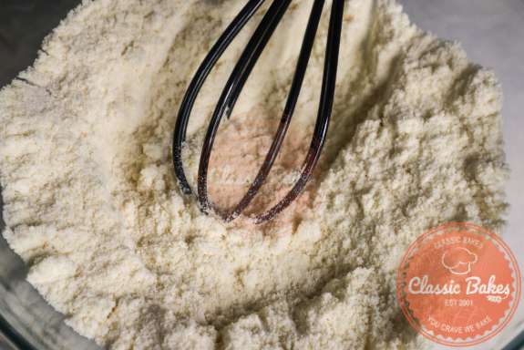 Almond flour, coconut flour, xanthan gum, salt, and sugar-free sweetener  being whisked in a bowl