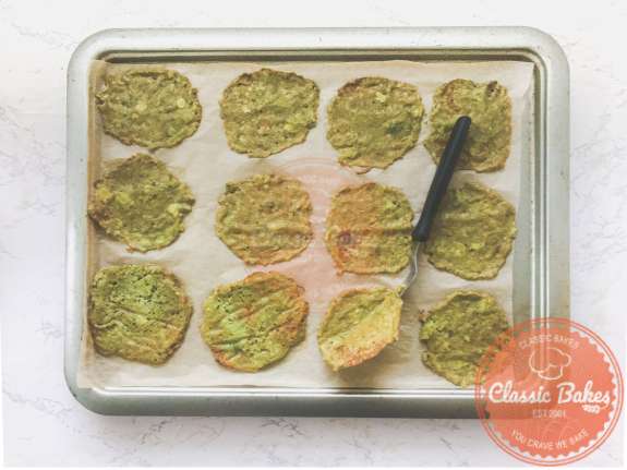 Avocado chips on a tray being flipped over using a spatula. 