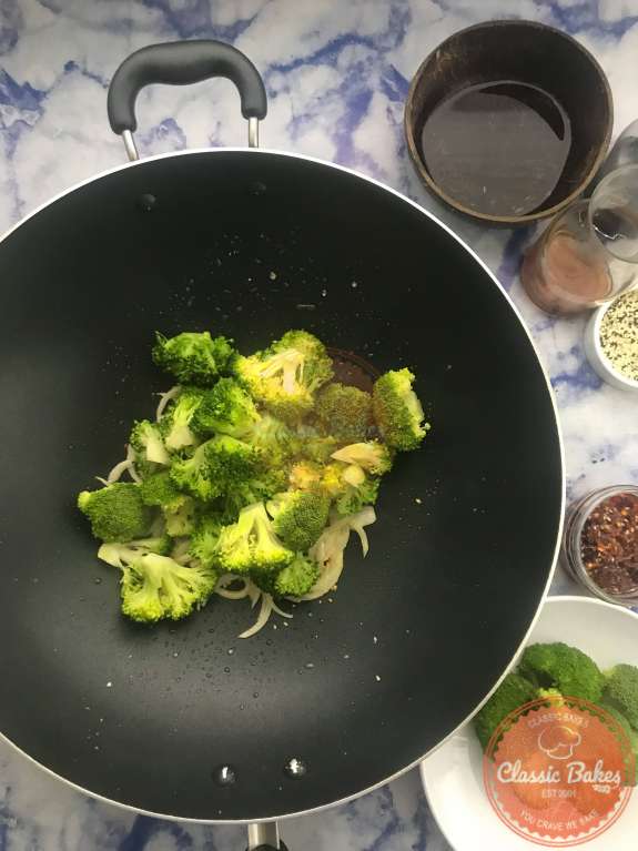 Broccoli being tossed with onions and garlic in a wok 