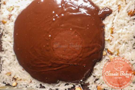Chocolate ganache being spread onto an almond joy cake. 