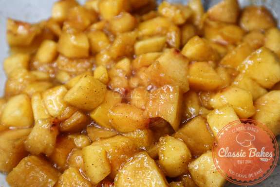 Diced peaches, sugar-free sweetener, and cinnamon macerating in a bowl. 