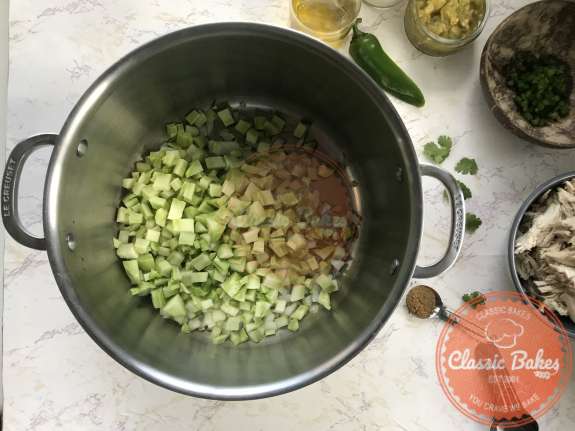 Onions, celery and broccoli stems being sauteed in a pot 