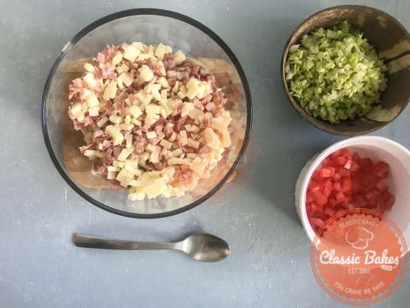 Overview of a bowl containing diced ham, salami and provolone cheese 