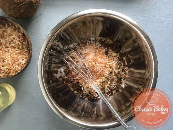 Overview of a bowl of dry coconut cupcake ingredients being mixed 