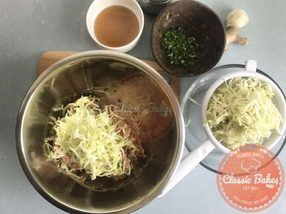 Overview of cabbage in a strainer being added to pork filling 