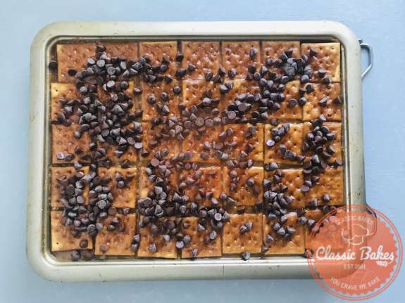 Overview of chocolate chips sprinkled on top of toffee crackers 