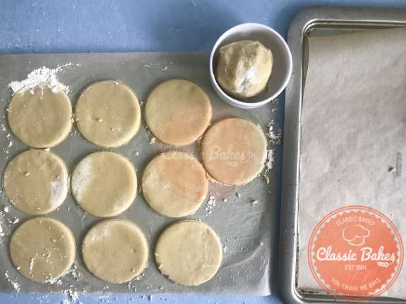 Overview of circles of tart dough next to a lined sheet tray