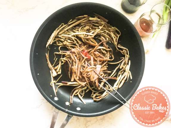 Overview of eggplant noodles being tossed with sambal and soy sauce  