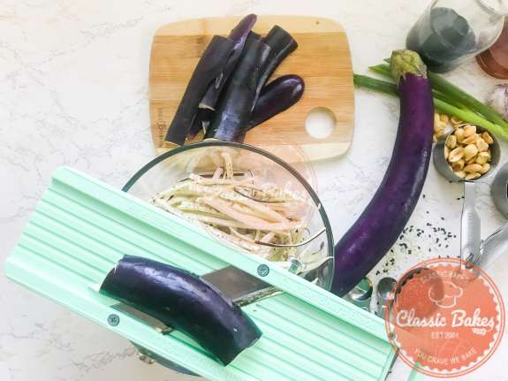 Overview of Japanese eggplant being sliced using a mandolin 