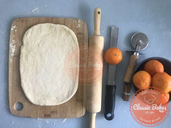 Overview of pizza dough rolled out into a rectangle next to a rolling pin