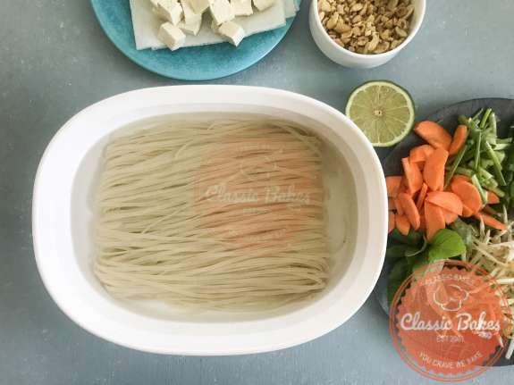 Overview of rice noodles soaking in a dish of hot water 