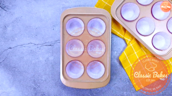 Overview of two six cup muffin tins lined with paper