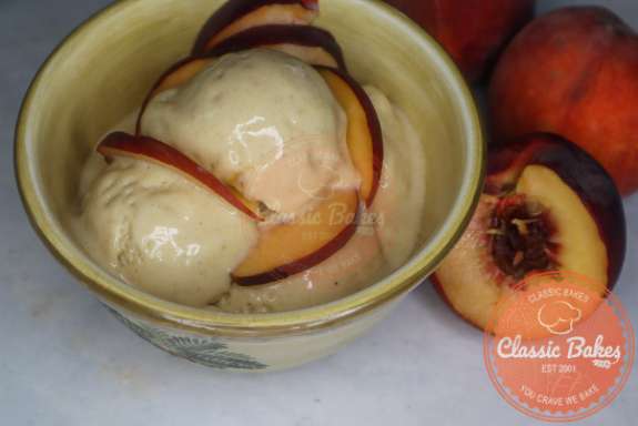 Peach ice cream in a bowl garnished with fresh peaches.