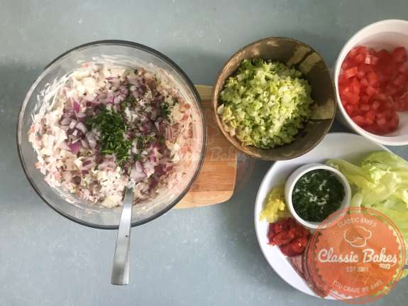 Red onions and parsley being added to hoagie dip 