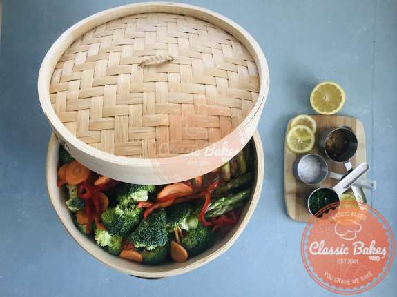 A steamer basket containing vegetables with a lid about to be steamed 