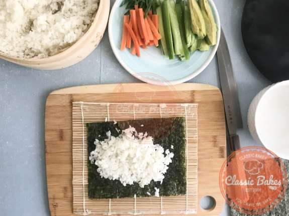Sushi rice being added to a sheet of nori 