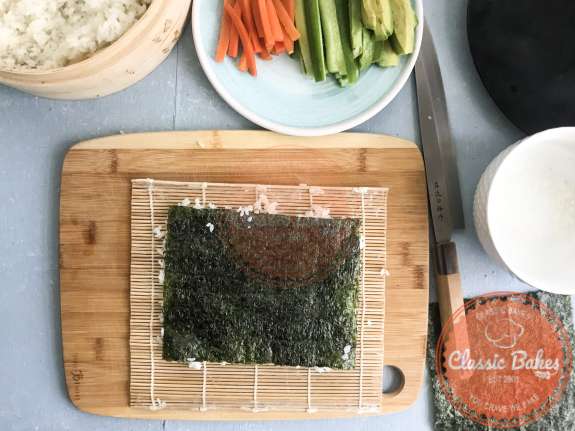 Sushi rice on a sheet of nori being flipped over