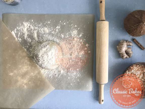 Tart dough lightly floured with a sheet of parchment paper next to it 