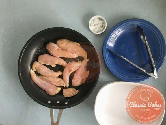 Overview of chicken being seared in a pan 