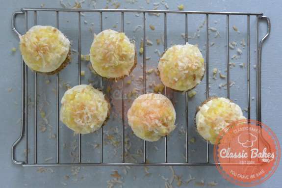 Overview of completed pina colada cupcakes on a cooling rack 