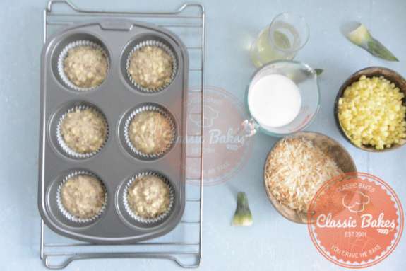 Overview of a muffin tin 3/4s filled with pina colada cupcake batter 