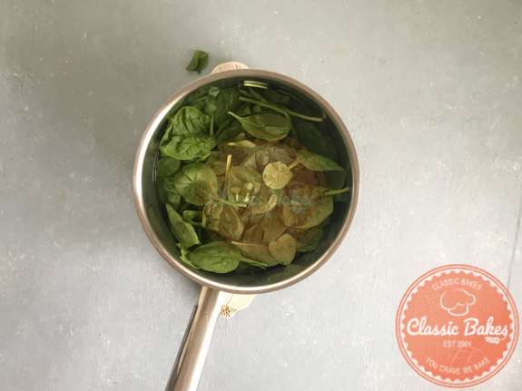 Spinach being added to a pot of boiling water 