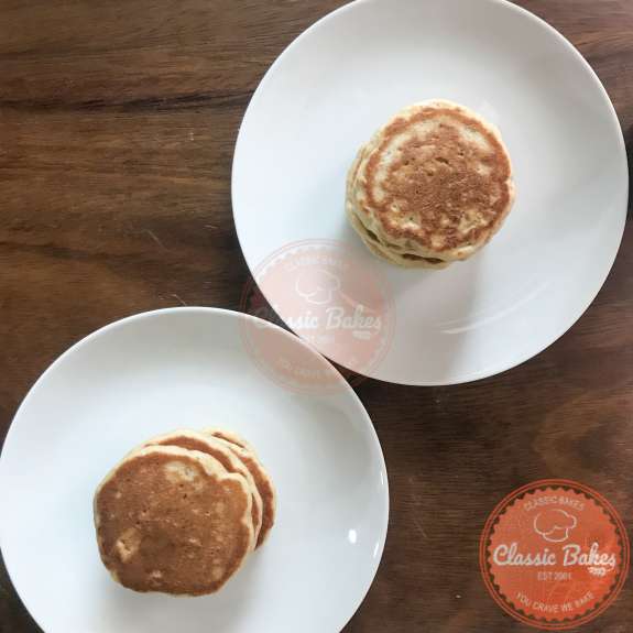 2 plates of pancakes being kept warm 