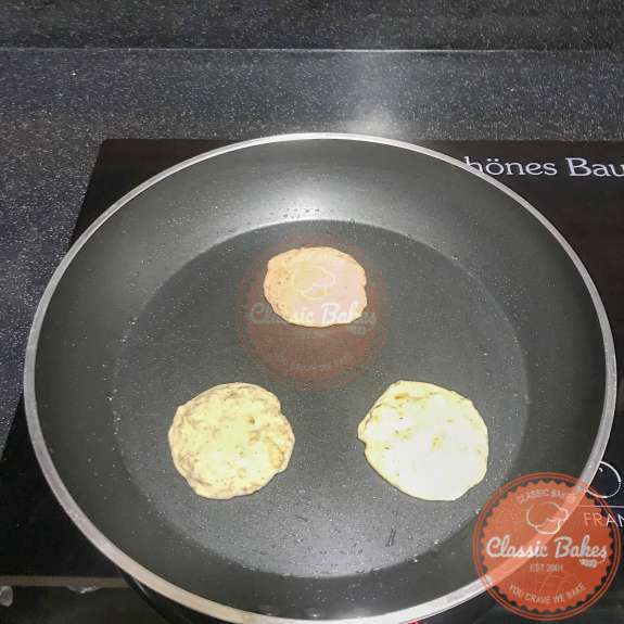 3 Pancakes being cooked in a pan sprayed with cooking oil 