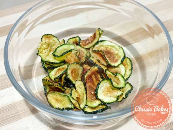 Overview of fresh zucchini chips in a bowl on a tabletop 
