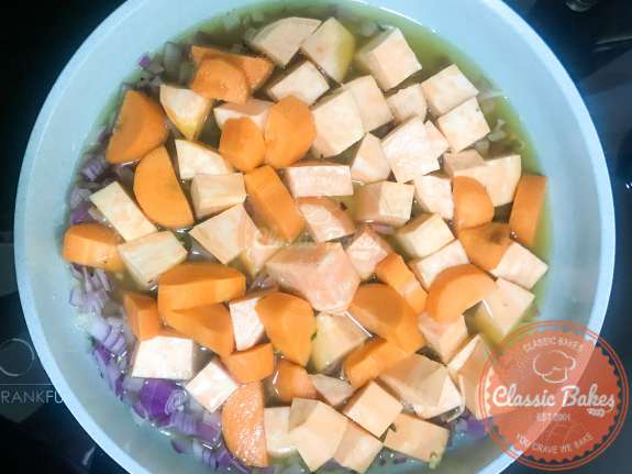 Diced carrots, sweet potatoes and vegetable broth being added to the soup 
