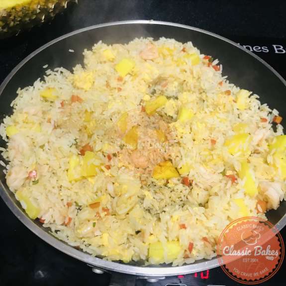 Eggs and pineapple shrimp fried rice being mixed with soy sauce