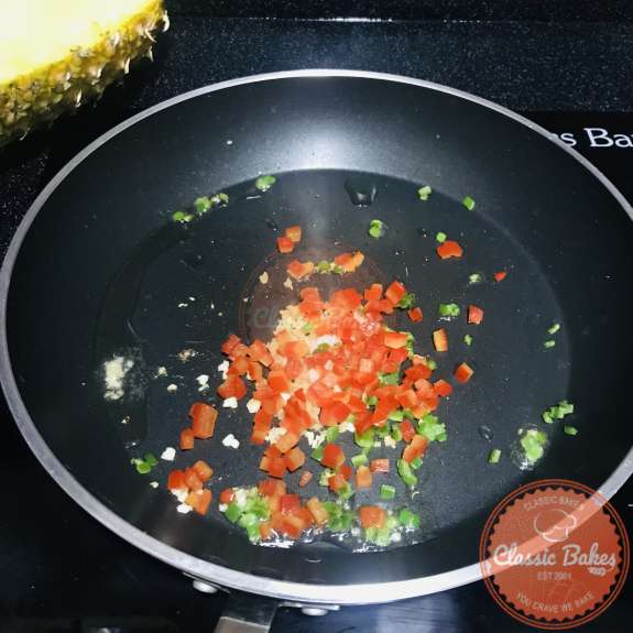 Ginger, garlic and peppers being cooked in a pan 