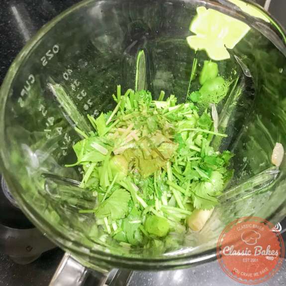 Lime juice and cilantro being added to hot sauce ingredients in a blender