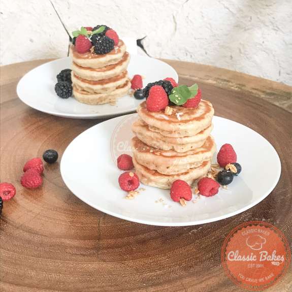 Side view of two stacks of pancakes with berries on top