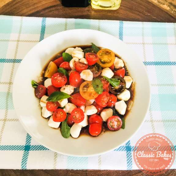 Overview of caprese salad with cherry tomatoes in a plate with balsamic dressing 
