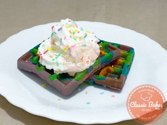 Front shot of Rainbow waffles with whipped cream and sprinkles