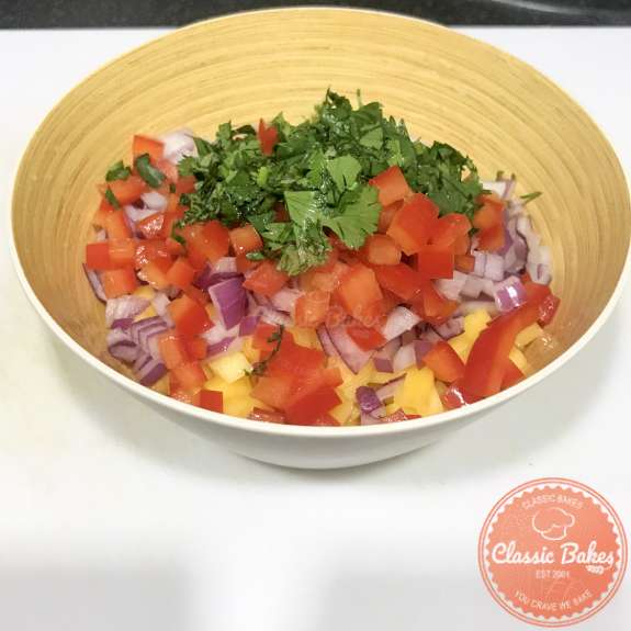 Side view of a bowl of mango salsa ingredients in a bowl 