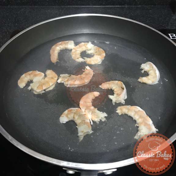 Side view of shrimp poaching in a pan of water