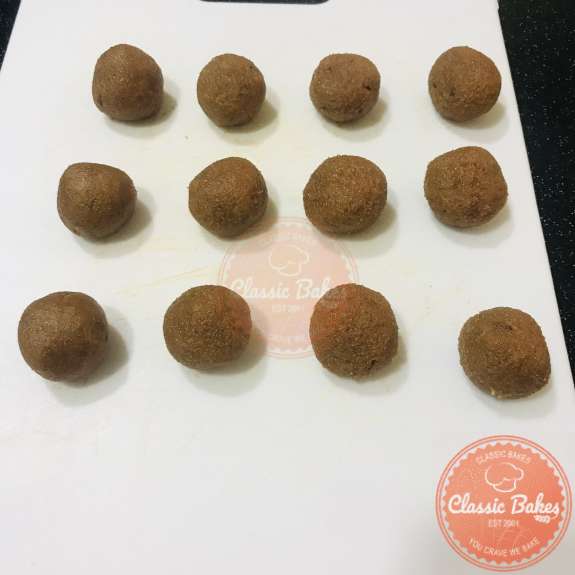 Side view of twelve tamarind balls on a cutting board